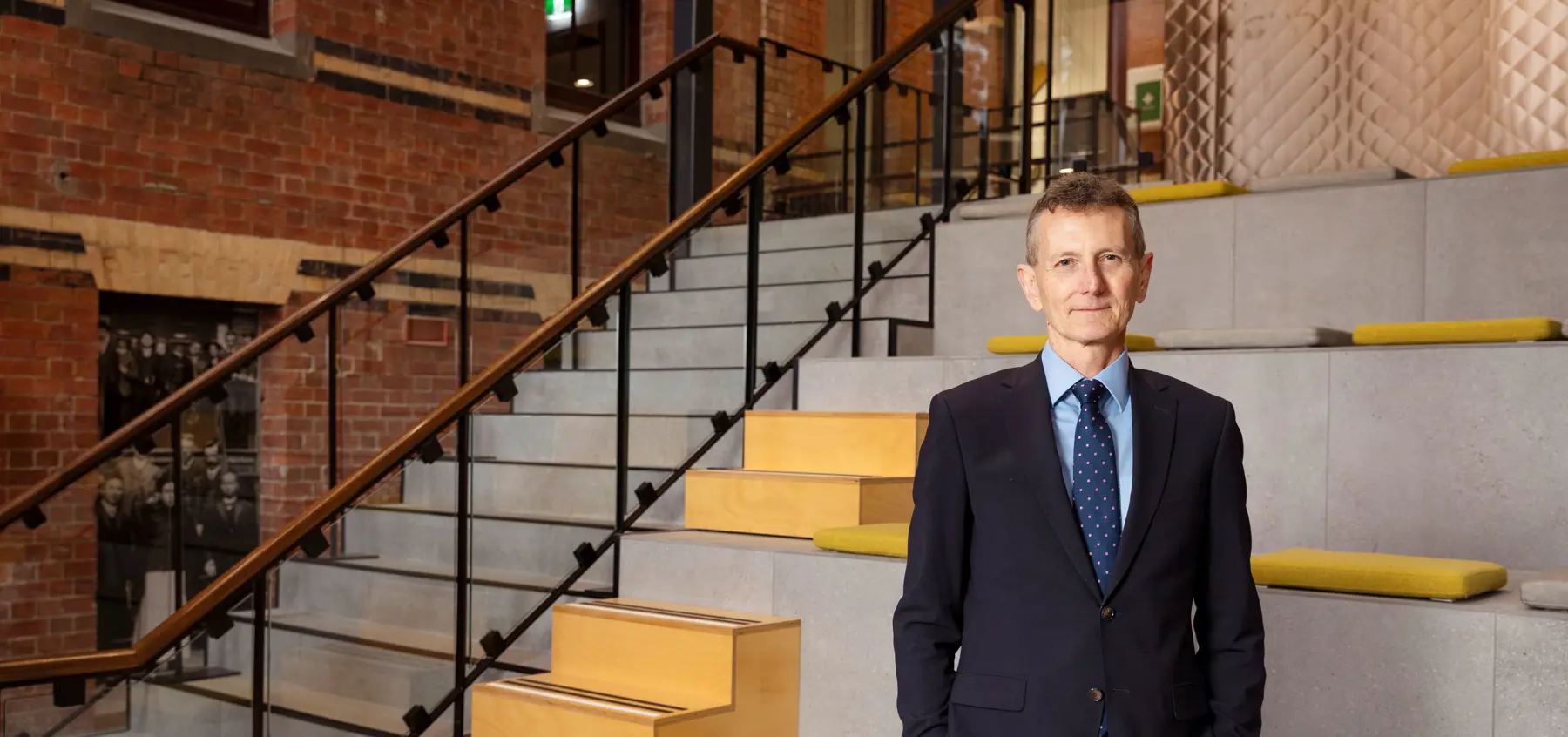 Man wearing a suit standing in front of a stairwell