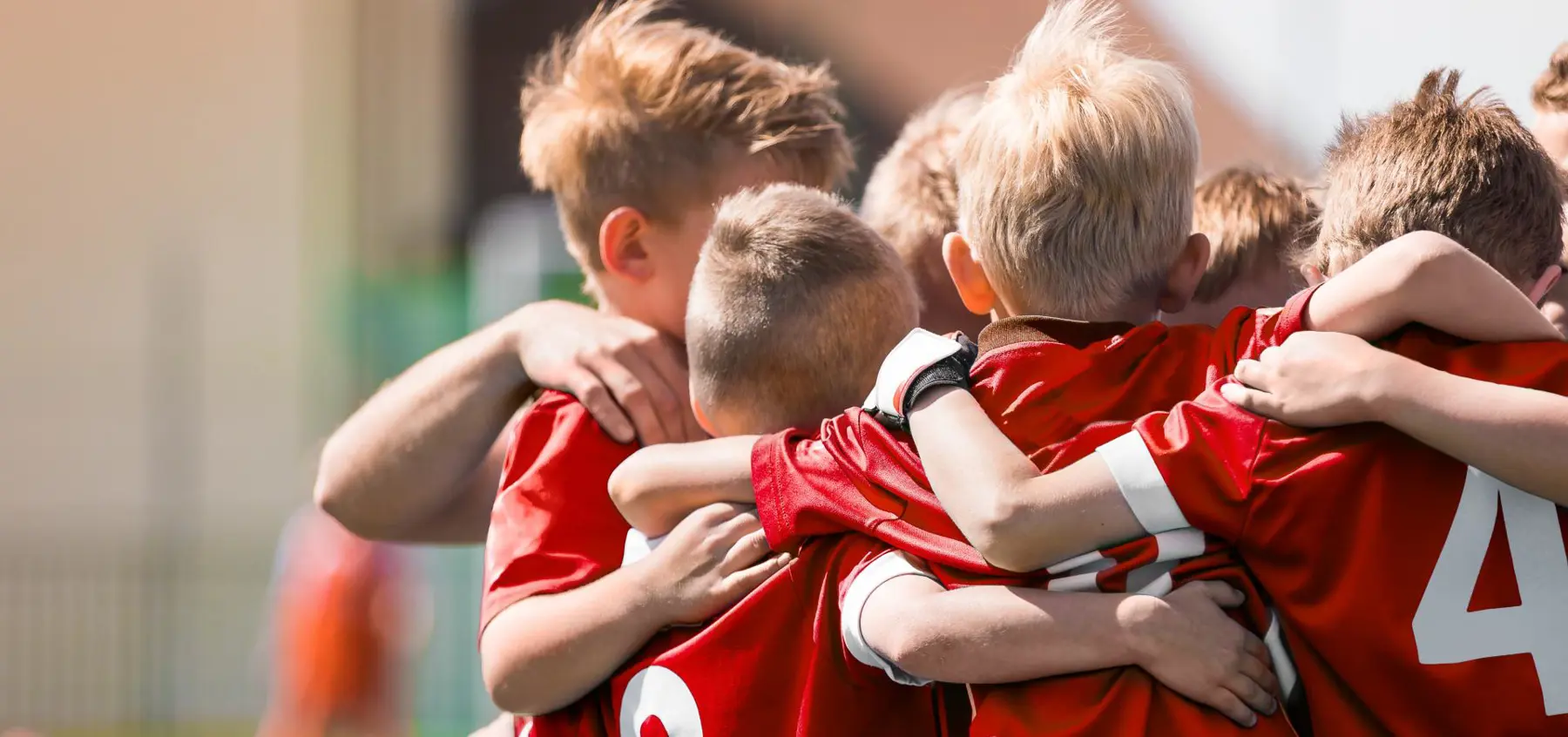 A boys soccer team wearing red tops in a huddle