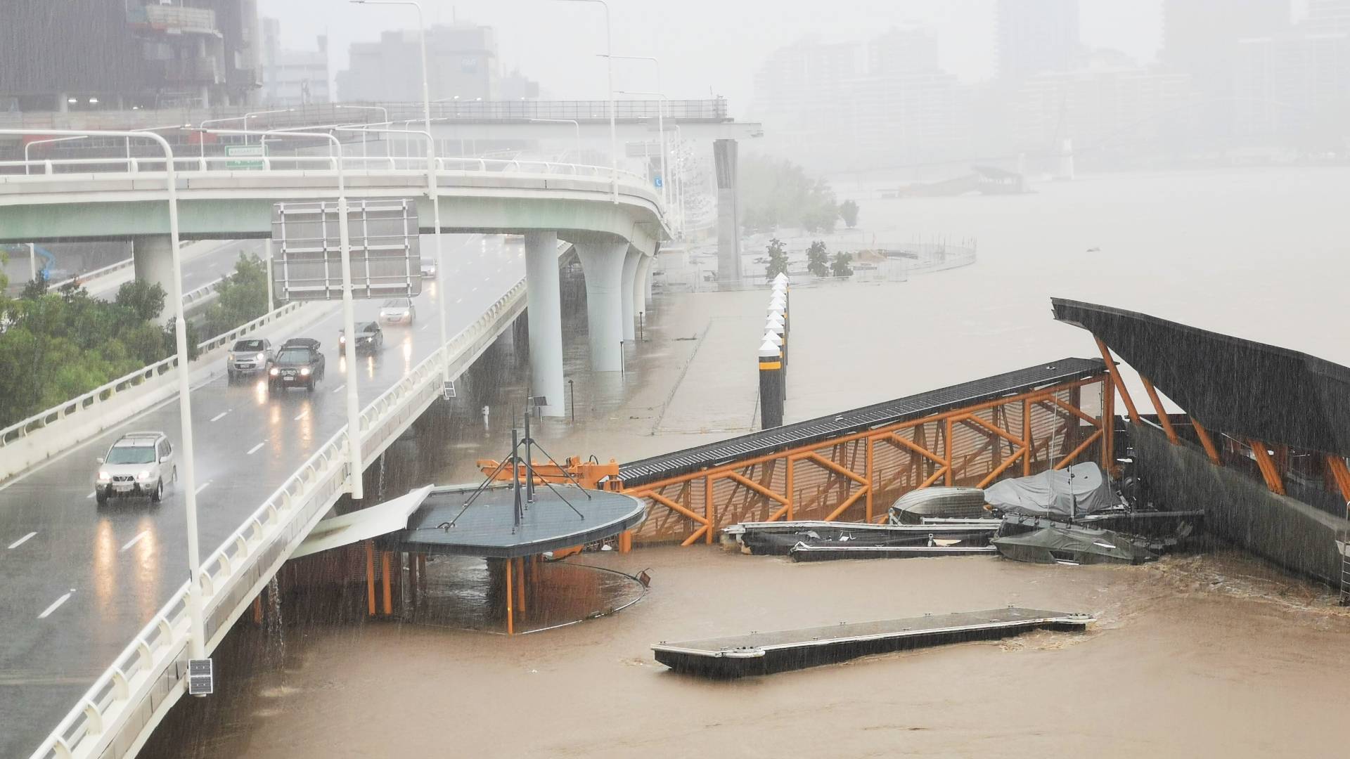 building destroyed by cyclone next to road bridge with cars on it