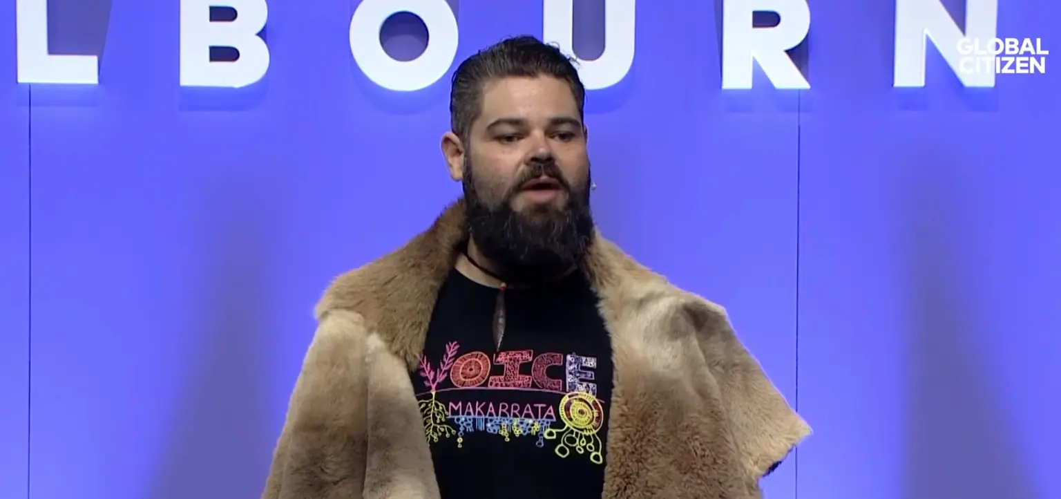 Indigenous man speaking in front of a Melbourne sign