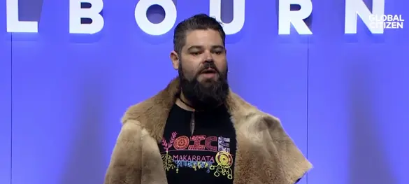 Indigenous man speaking in front of a Melbourne sign