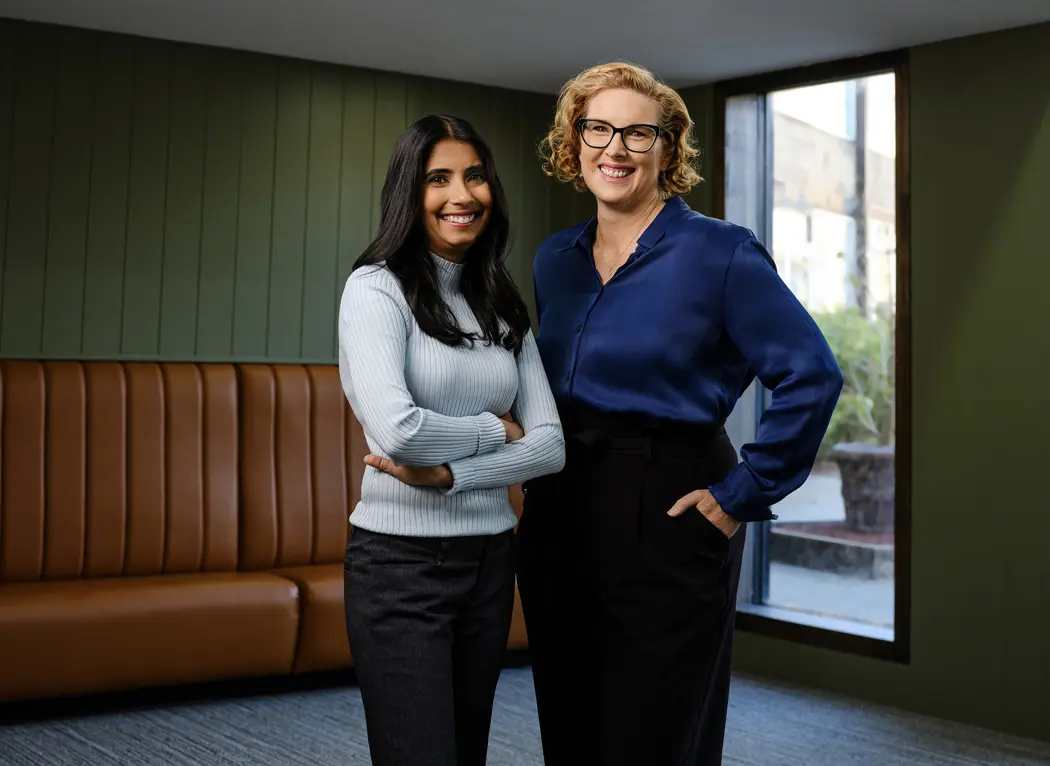 Photo of two people standing in front of a small window in a vintage looking room.