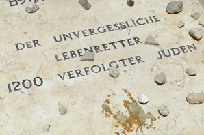 "Photograph showing the grave of Oskar Schindler, covered with small stones placed by visitors, with engraved text visible on the headstone." (Fig. 1. From Details of Grave of Oskar Schindler, by Adam Jones, Flickr, 1 May 2011, http://www.flickr.com/photos/adam_jones/5676126945. Licensed under CC BY 2.0.)