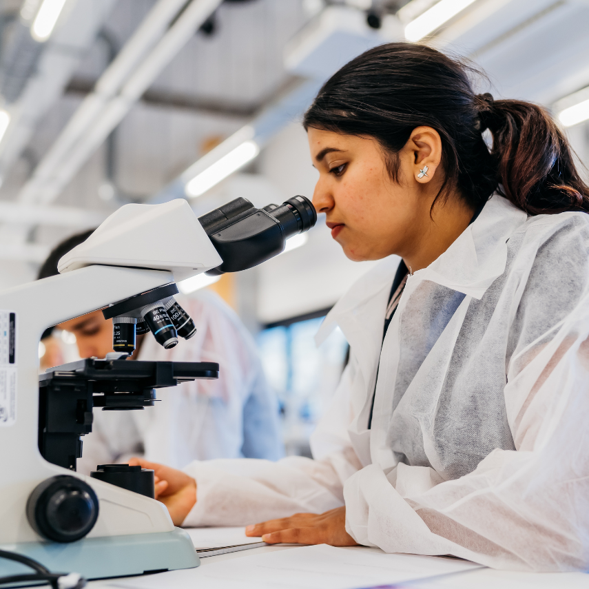 A research student is looking through a microscope at a professional lab