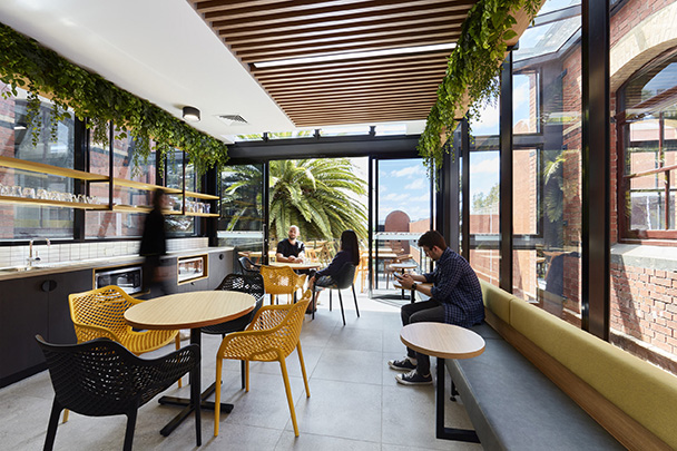 Students in a modern eating area with architectural features and greenery 
