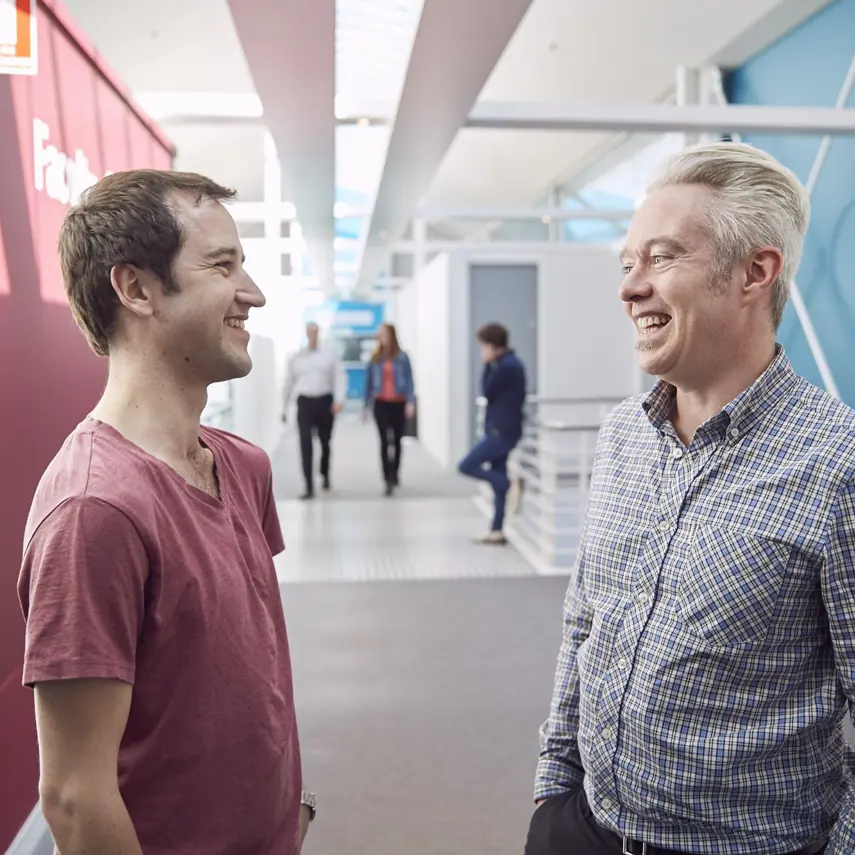 Photo of two people talking in a modern hallway