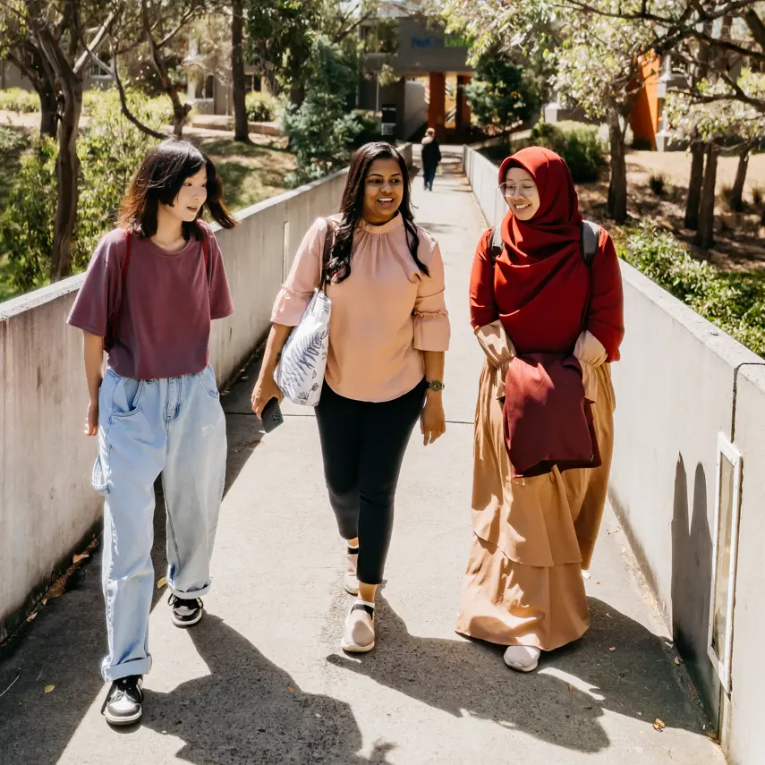 Three students walking along outside