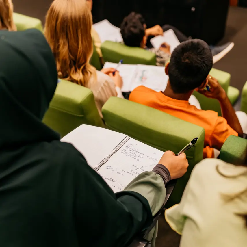 The backs of students sitting in a lecture theatre.