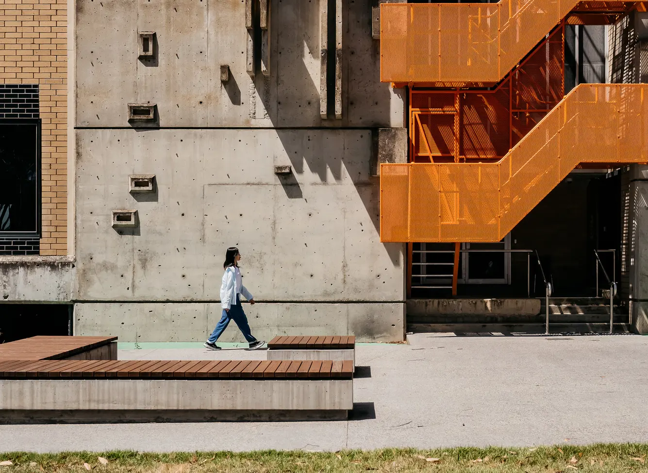 Person walking near modern building on Mt Helen Campus.